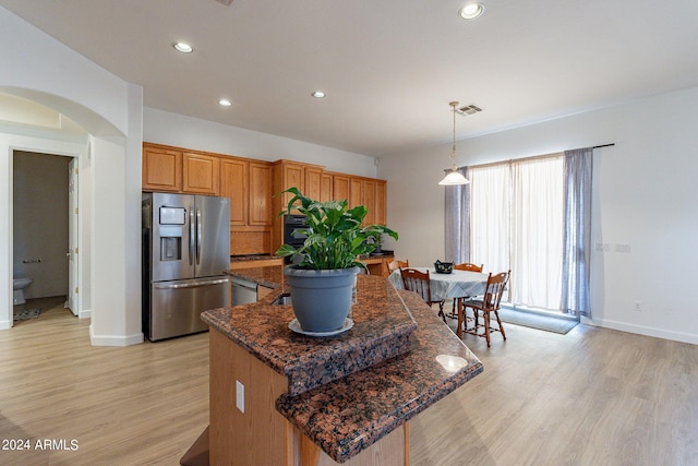 kitchen featuring light hardwood / wood-style flooring, hanging light fixtures, a kitchen island, and stainless steel fridge with ice dispenser