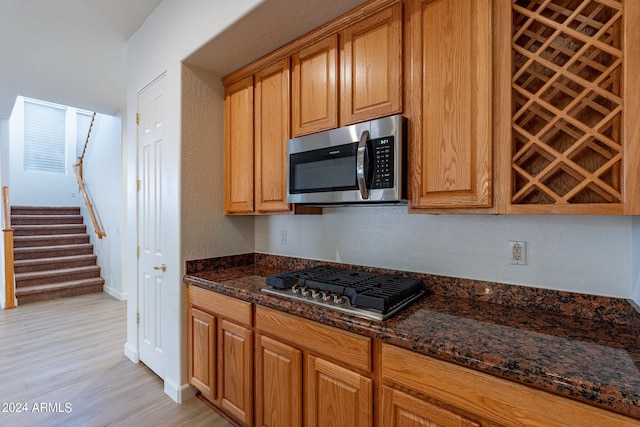 kitchen with dark stone countertops, light wood-type flooring, and appliances with stainless steel finishes