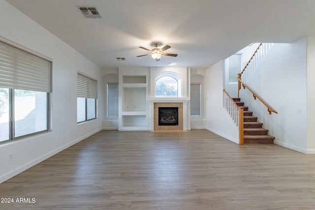 unfurnished living room featuring a fireplace, ceiling fan, light hardwood / wood-style flooring, and built in shelves