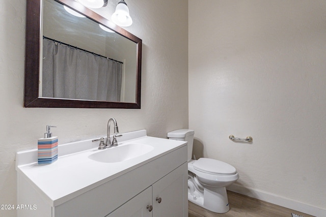 bathroom featuring wood-type flooring, toilet, vanity, and a shower with shower curtain