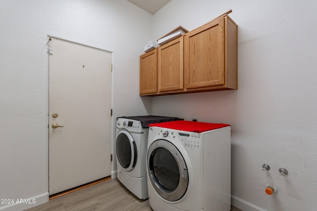 laundry room with light hardwood / wood-style floors, washing machine and dryer, and cabinets