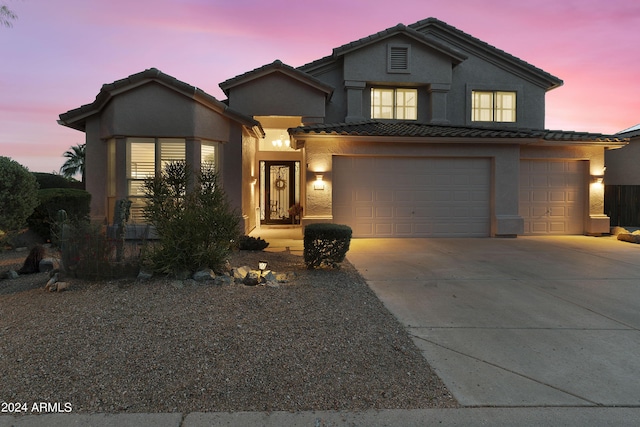 traditional-style home featuring a garage, stucco siding, driveway, and a tile roof