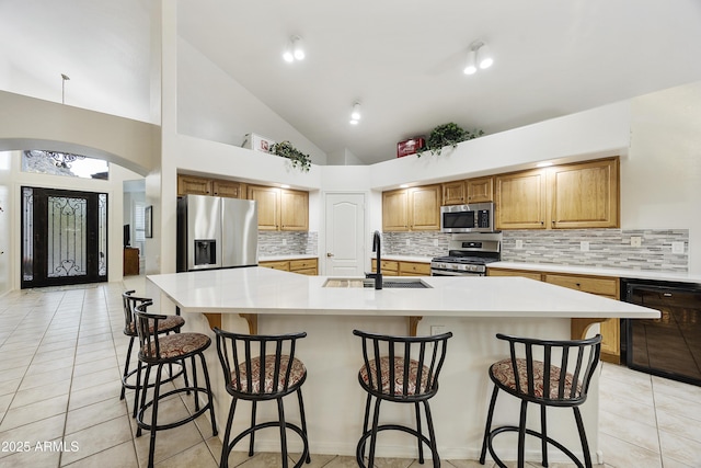 kitchen with a spacious island, light tile patterned floors, a sink, appliances with stainless steel finishes, and backsplash