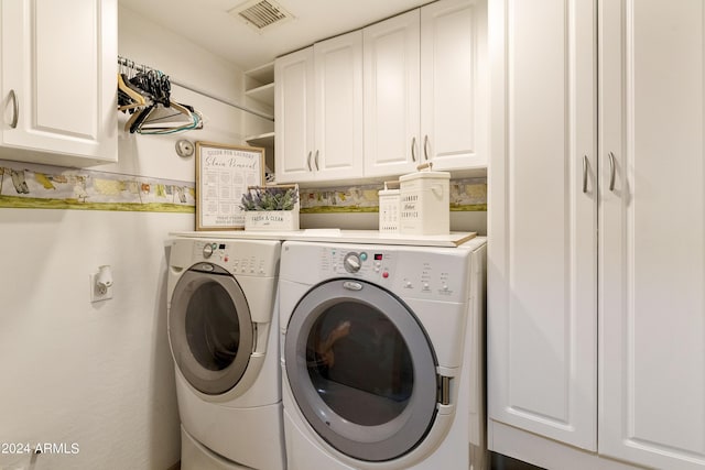 clothes washing area with visible vents, cabinet space, and washing machine and clothes dryer