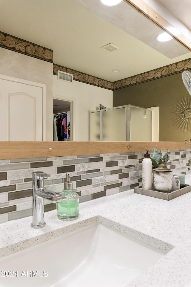 interior details featuring a walk in closet, backsplash, visible vents, a shower stall, and vanity