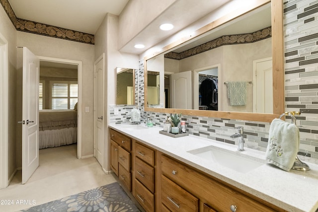 bathroom featuring connected bathroom, a walk in closet, a sink, double vanity, and backsplash