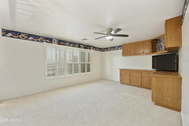 interior space with a ceiling fan, light colored carpet, and visible vents