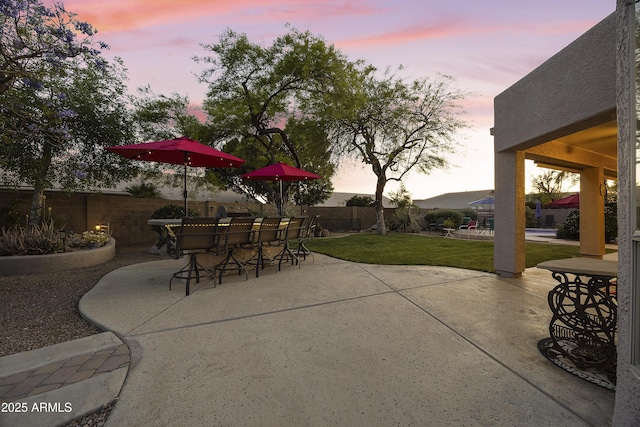 patio terrace at dusk with a lawn and fence