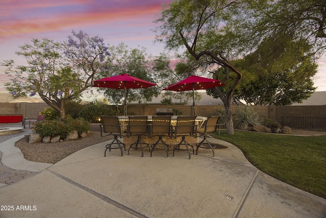 patio terrace at dusk featuring a fenced backyard