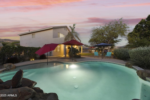 pool at dusk featuring a patio and a fenced in pool