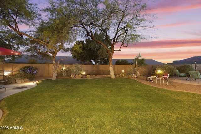 yard at dusk with a fenced backyard and a patio area