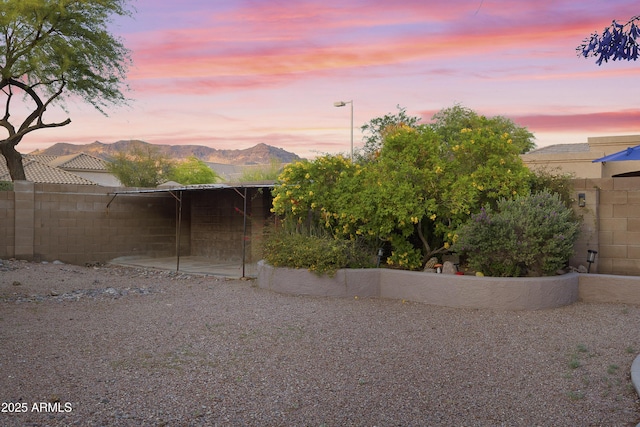 property exterior at dusk featuring fence and a mountain view