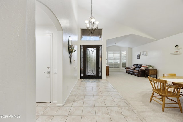 foyer with arched walkways, light tile patterned floors, baseboards, a chandelier, and light carpet