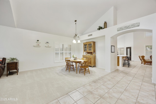 dining area featuring visible vents, light tile patterned flooring, light carpet, high vaulted ceiling, and arched walkways