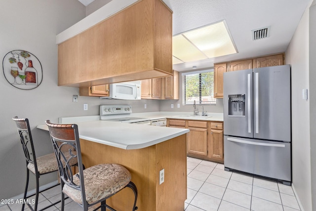 kitchen with electric range oven, a breakfast bar, sink, stainless steel fridge, and kitchen peninsula