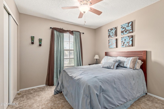 carpeted bedroom featuring ceiling fan, a textured ceiling, and a closet