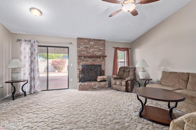 carpeted living room with ceiling fan, lofted ceiling, a fireplace, and a textured ceiling