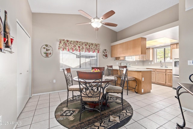 tiled dining space featuring ceiling fan, sink, and high vaulted ceiling