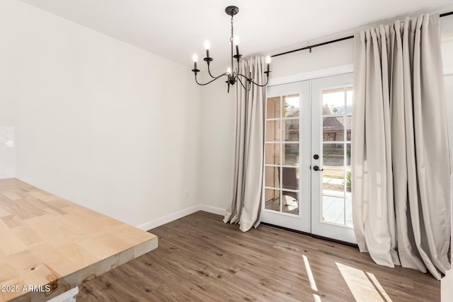 unfurnished dining area featuring hardwood / wood-style floors, a notable chandelier, and french doors