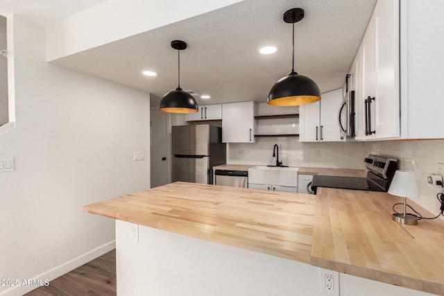 kitchen featuring hanging light fixtures, appliances with stainless steel finishes, sink, and white cabinets