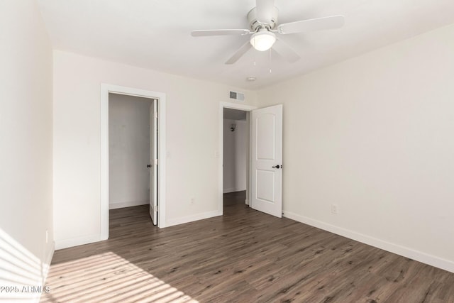 unfurnished bedroom featuring ceiling fan, dark hardwood / wood-style flooring, a closet, and a spacious closet