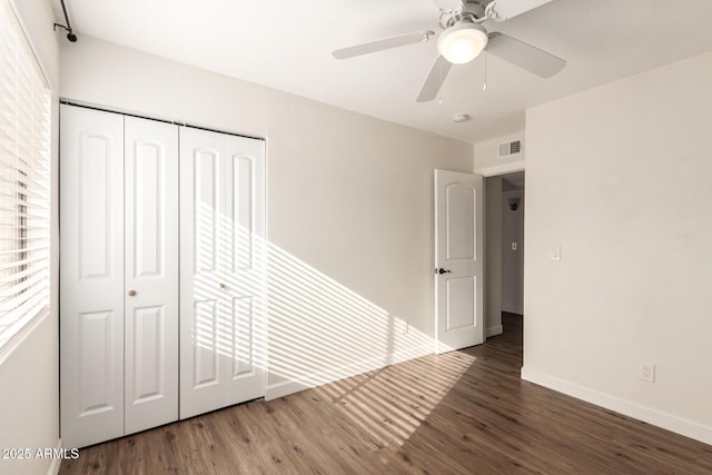 unfurnished bedroom featuring dark wood-type flooring, a closet, and ceiling fan