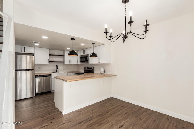 kitchen featuring white cabinetry, appliances with stainless steel finishes, decorative light fixtures, and kitchen peninsula