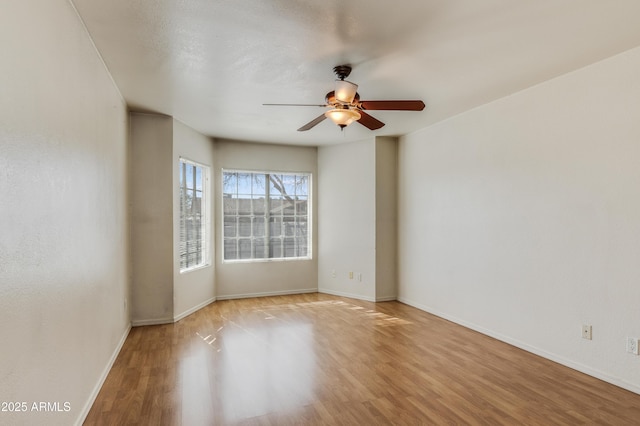 empty room with baseboards, a ceiling fan, and wood finished floors