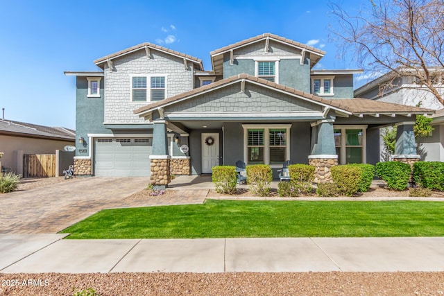 craftsman-style house featuring decorative driveway, a tile roof, stucco siding, a front yard, and a garage