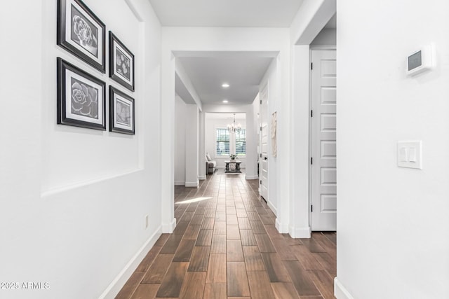 hall with a chandelier, recessed lighting, dark wood finished floors, and baseboards