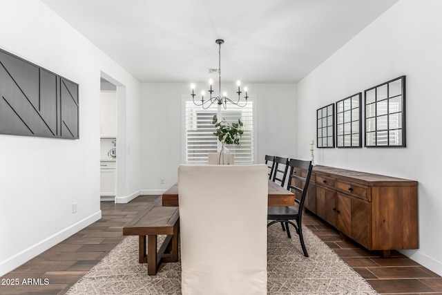 dining area featuring wood tiled floor, baseboards, and a notable chandelier