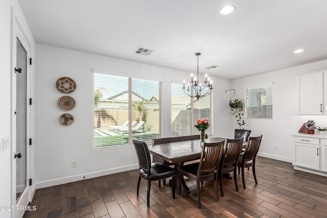 dining room with a chandelier, dark wood-type flooring, visible vents, and baseboards