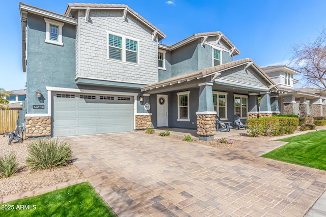 craftsman-style house featuring decorative driveway, stucco siding, an attached garage, stone siding, and a tiled roof