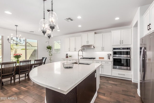 kitchen featuring a chandelier, under cabinet range hood, a sink, visible vents, and appliances with stainless steel finishes