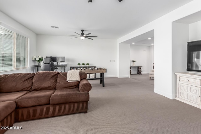 living area featuring carpet floors, visible vents, baseboards, and a ceiling fan