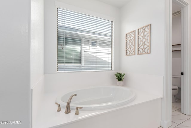 bathroom with a garden tub and toilet