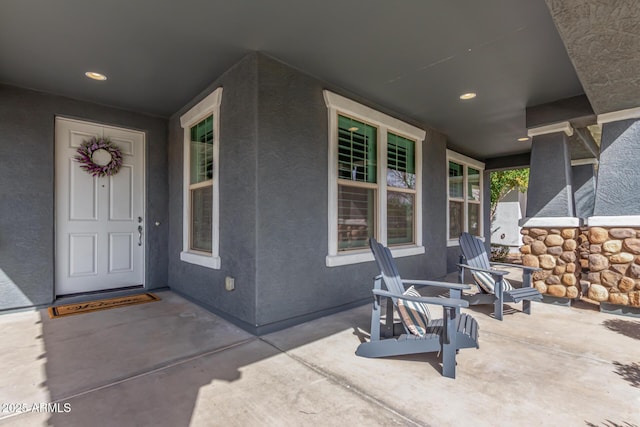 doorway to property with covered porch and stucco siding