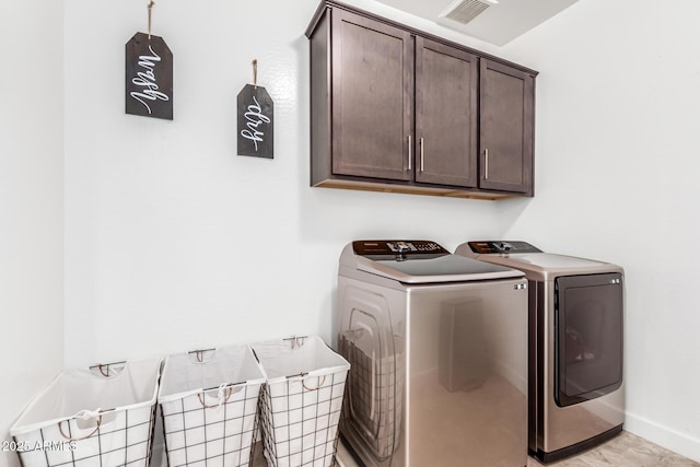 clothes washing area with cabinet space, washing machine and dryer, visible vents, and baseboards