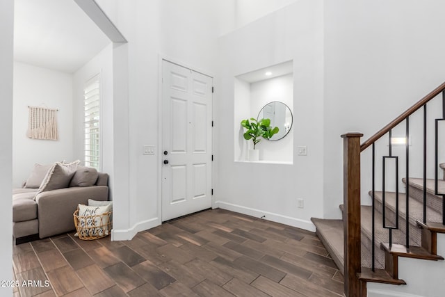 entrance foyer featuring wood tiled floor, stairway, and baseboards