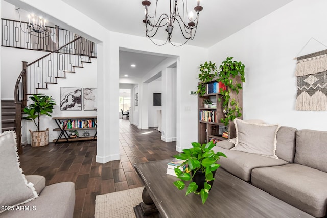 living room with baseboards, stairway, wood finished floors, and an inviting chandelier