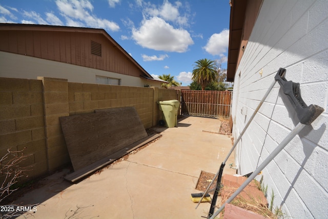 view of side of property with concrete block siding, a fenced backyard, and a patio area