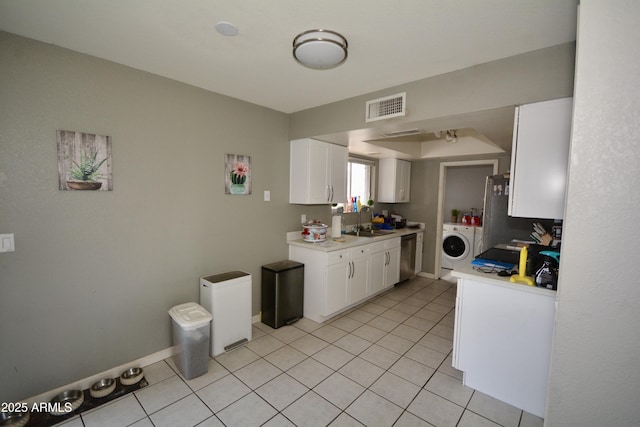 kitchen with visible vents, white cabinets, light tile patterned floors, washer / dryer, and dishwasher