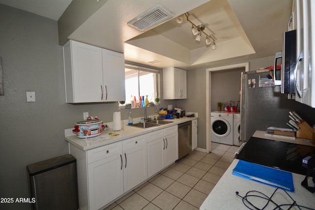 kitchen with visible vents, washer and clothes dryer, appliances with stainless steel finishes, a raised ceiling, and a sink