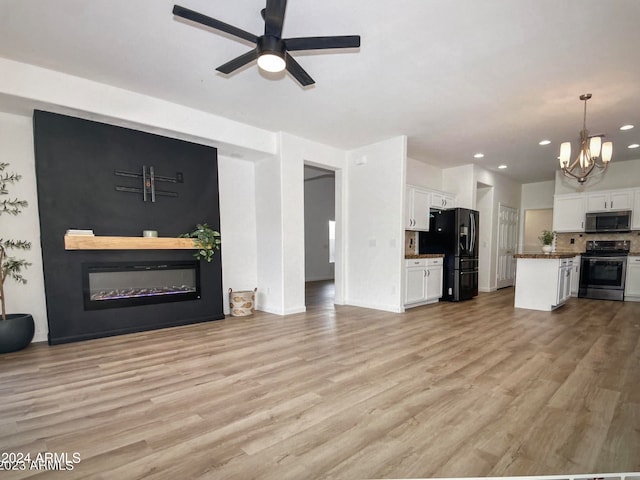 unfurnished living room featuring light hardwood / wood-style floors and ceiling fan with notable chandelier