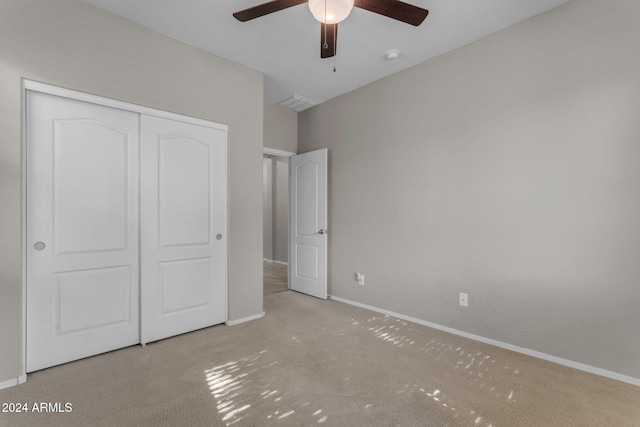 unfurnished bedroom with ceiling fan, a closet, and light carpet