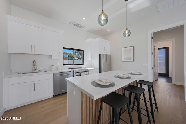 6126 E Charter Oak Rd, Scottsdale, AZ 85254 - kitchen with stainless steel appliances, light wood-style floors, white cabinetry, a kitchen bar, and recessed lighting