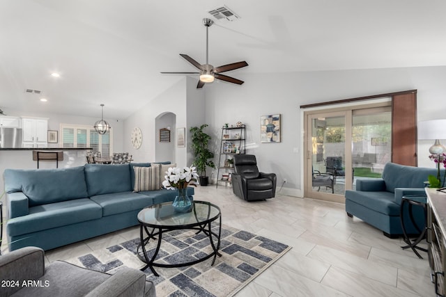 living room with ceiling fan with notable chandelier, a healthy amount of sunlight, and vaulted ceiling