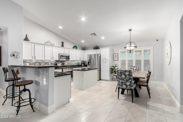 kitchen featuring kitchen peninsula, appliances with stainless steel finishes, white cabinetry, hanging light fixtures, and lofted ceiling