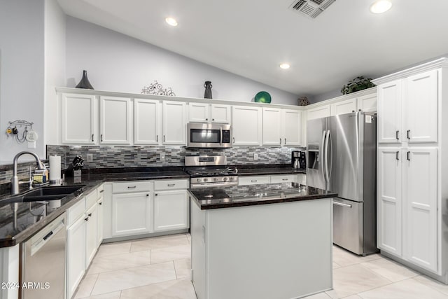 kitchen with stainless steel appliances, vaulted ceiling, sink, dark stone countertops, and a center island