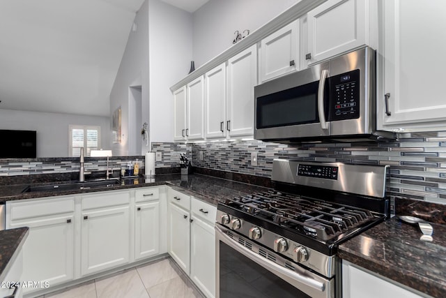 kitchen with dark stone countertops, white cabinetry, sink, and appliances with stainless steel finishes